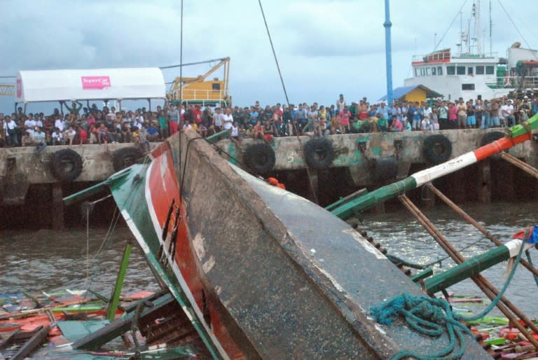 Residents watch as the Kim Nirvana ferry is lifted by a crane after it was towed to the pier in Ormoc City, central Philippines, on July 3, 2015, a day after it capsized