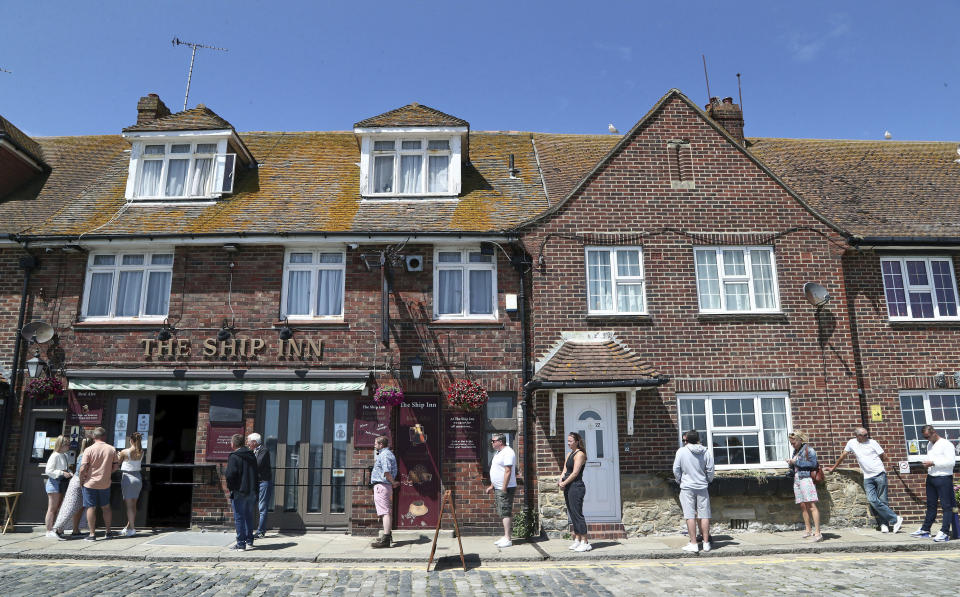 People queue for take away drinks at The Ship Inn in Folkestone, England, Sunday June 21, 2020. Pubs in England are still closed to serve drinks in the premises due to lockdown restrictions imposed to stem the spread of coronavirus. (Gareth Fuller/PA via AP)