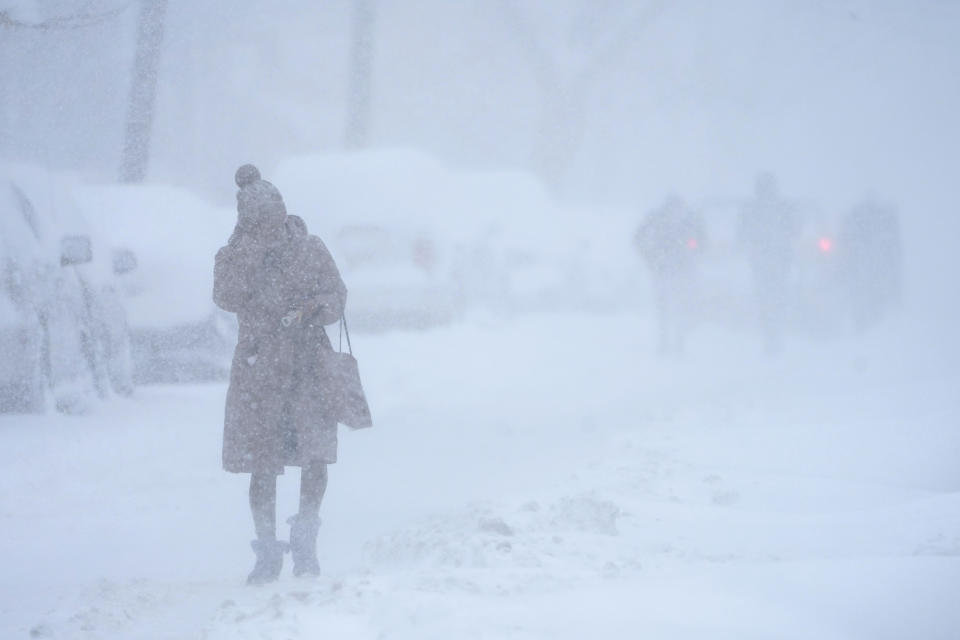 A woman tries to protect her face from blowing snow while walking in white-out conditions in Jersey City, N.J., Monday, Feb. 1, 2021. A sprawling, lumbering winter storm is walloping the Eastern U.S., shutting down coronavirus vaccination sites, closing schools and halting transit. With flakes falling since Sunday evening, New York City and northern New Jersey braced for as much as 22 inches of snow, and parts of New England for a foot or more. (AP Photo/Seth Wenig)