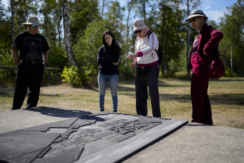 Israeli Olympic racewalker Shaul Ladany, second right, talks to his sister Martha Flatto-Zemanek, right, his granddaughter Raz Sharifi, second left, and nephew Assaf Flatto in front of a miniature model of the former Nazi concentration camp Bergen-Belsen inside the former camp in Bergen, Germany, Saturday, Sept. 3, 2022. Shaul Ladany survived a Nazi concentration camp and narrowly escaped the massacre of the Israeli athletes at the 1972 Olympic Games in Munich. Both attempts to murder him happened on German soil in the last century. Many decades later, the 86-year-year old Jew has returned to visit the two places where he narrowly escaped death. (AP Photo/Markus Schreiber)