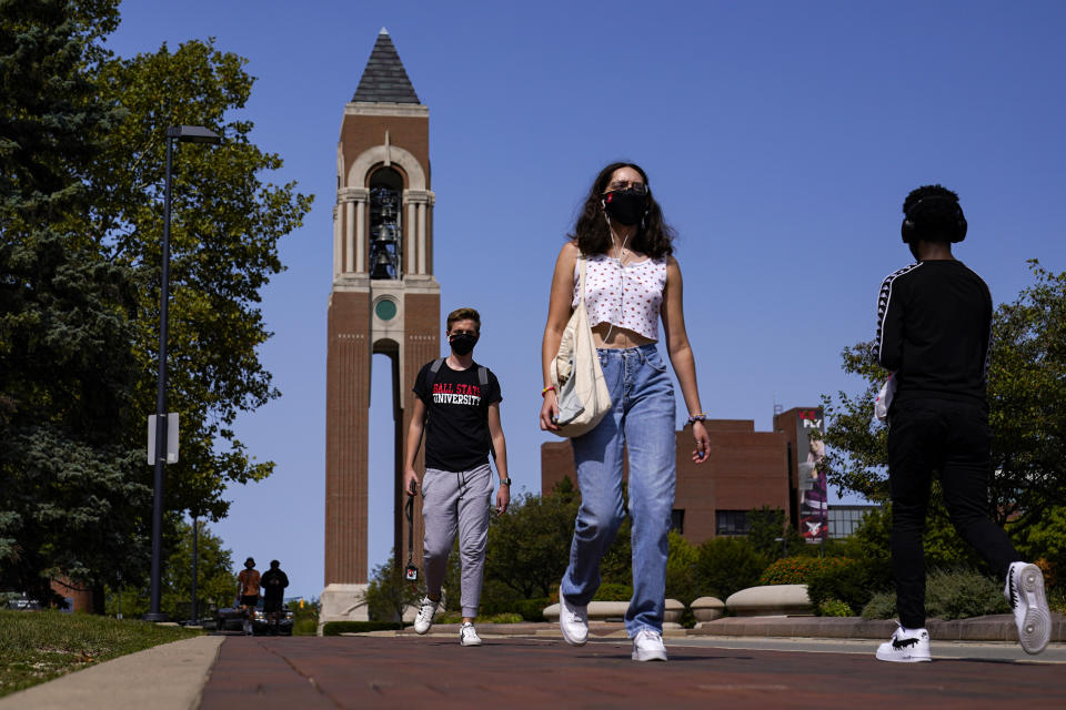 FILE - Masked students walk through the campus of Ball State University in Muncie, Ind., Thursday, Sept. 10, 2020. Colleges across the country are struggling to salvage the fall semester as campus coronavirus cases skyrocket and tensions with local health leaders flare. Schools have locked down dorms, imposed mask mandates, barred student fans from football games and toggled between online and in-person classes. (AP Photo/Michael Conroy)