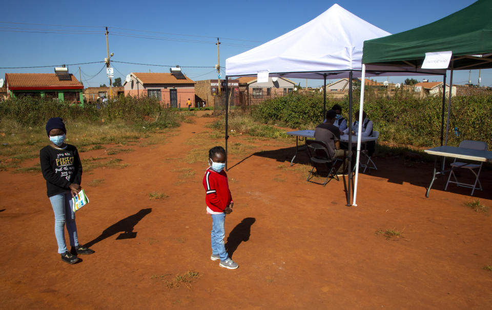 Children queue on a dusty soccer field to be screened and tested for COVID-19 at Lenasia South, south Johannesburg, South Africa, Tuesday, April 21, 2020, during a campaign aimed to combat the spread of Coronavirus. (AP Photo/Themba Hadebe)