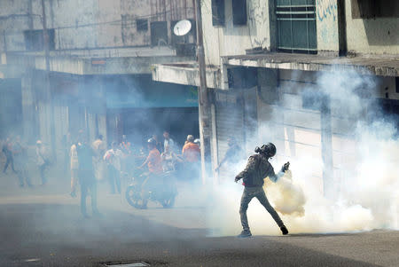 A demonstrator throws back a gas canister while clashing with security forces during a rally against Venezuelan President Nicolas Maduro's government and to commemorate the 61st anniversary of the end of the dictatorship of Marcos Perez Jimenez in Tachira, Venezuela January 23, 2019. REUTERS/Carlos Eduardo Ramirez