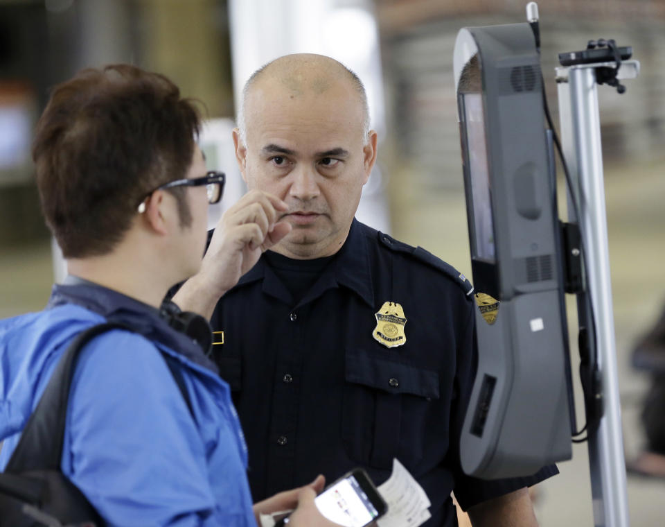 A U.S. Customs and Border Protection officer talks to a passenger at a face recognition kiosk at&nbsp;George Bush Intercontinental Airport in Houston in July 2017. (Photo: ASSOCIATED PRESS)