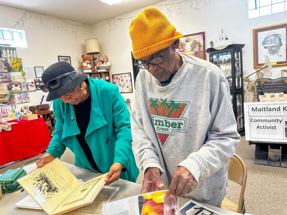 Community activist and Royal native Maitland Keiler flips through his personal history books of Royal with Gwendolyn Roach during a recent visit to the Alonzo A. Young Sr. Enrichment and Historical Center. (Aallyah Wright/Capital B)