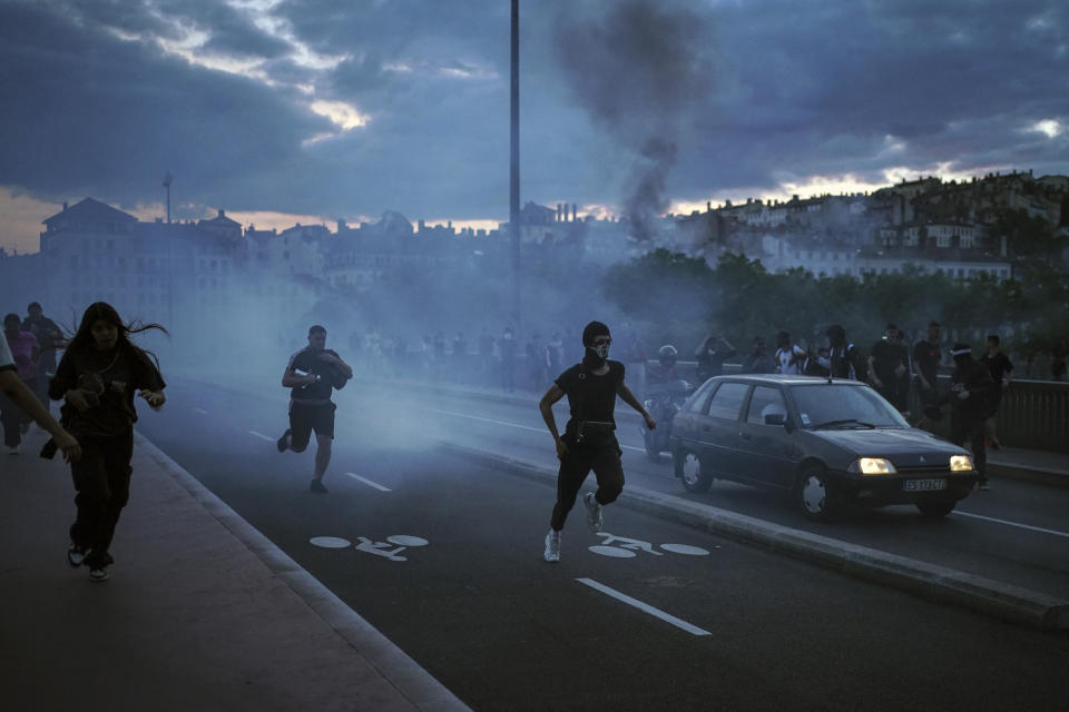 People run away during clashes with police in the center of Lyon, central France, Friday, June 30, 2023. French President Emmanuel Macron urged parents Friday to keep teenagers at home and proposed restrictions on social media to quell rioting spreading across France over the fatal police shooting of a 17-year-old driver. Writing on wall reads in French "Justice for Nahel" (AP Photo/Laurent Cipriani)