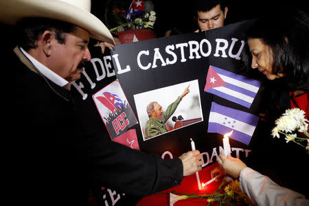 Honduras' former president Manuel Zelaya (2nd L) places candle beside a picture of Fidel, pay tribute, following the announcement of the death of Cuban revolutionary leader Fidel Castro, in Tegucigalpa, Honduras November 26, 2016. REUTERS/Jorge Cabrera