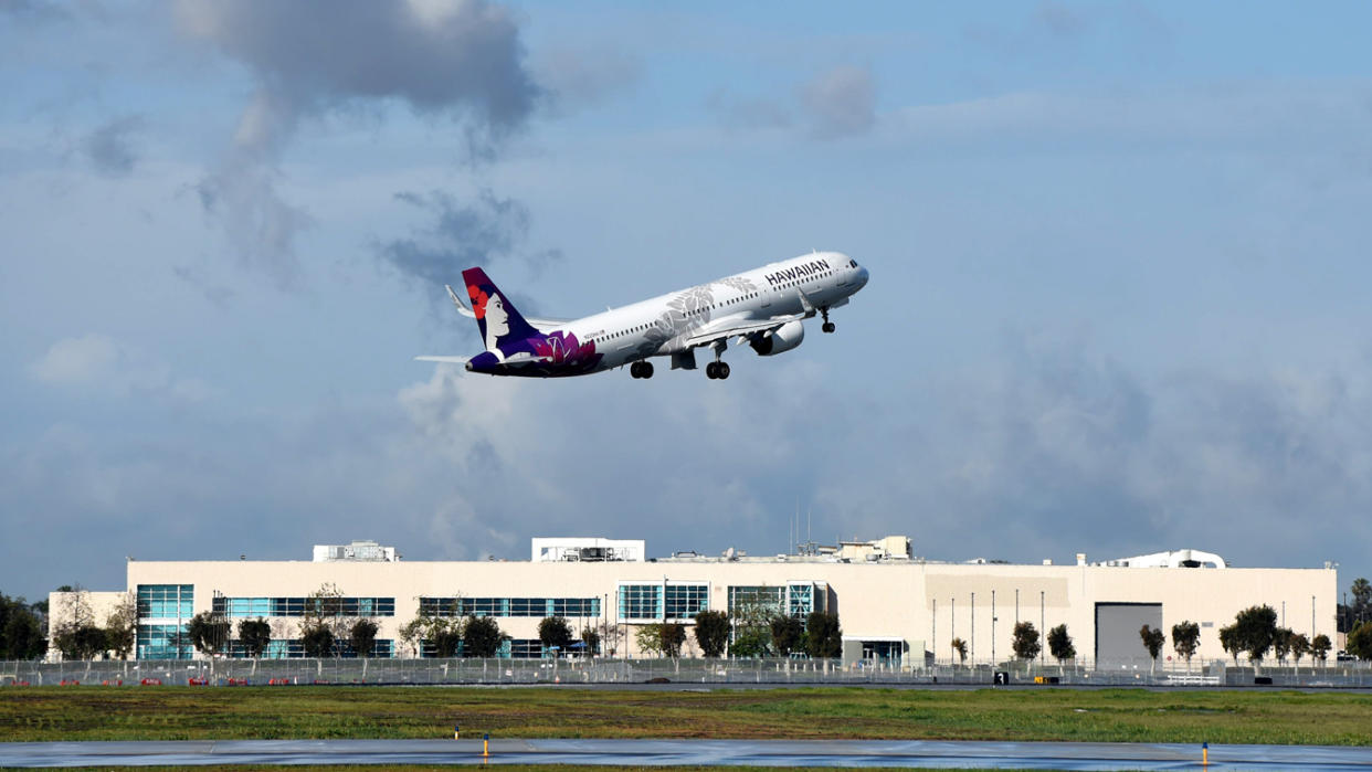 A Hawaiian Airlines jet takes off, with a rain cloud just forming.