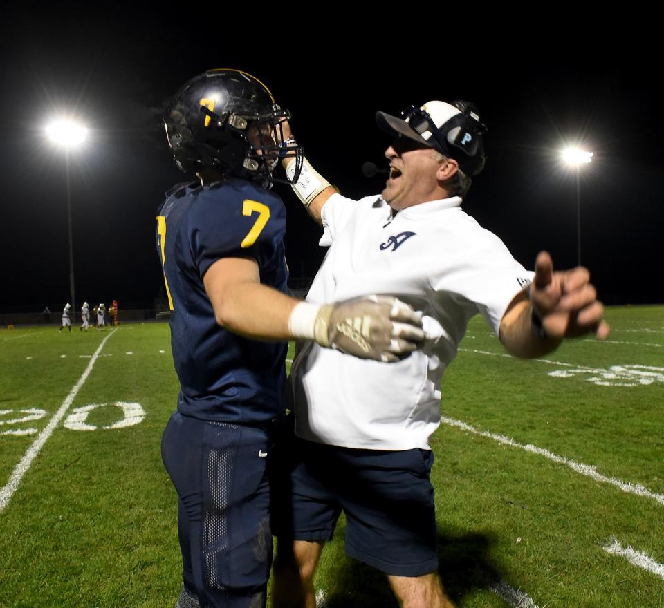 Jack Mills of Airport chess bumps Airport defense coordinator Derek Anderson after Mills picked up a fumble and ran it in for at touchdown against Detroit East English during a 70-18 Airport rout in a Division 4 playoff game on Friday, October 27, 2023.