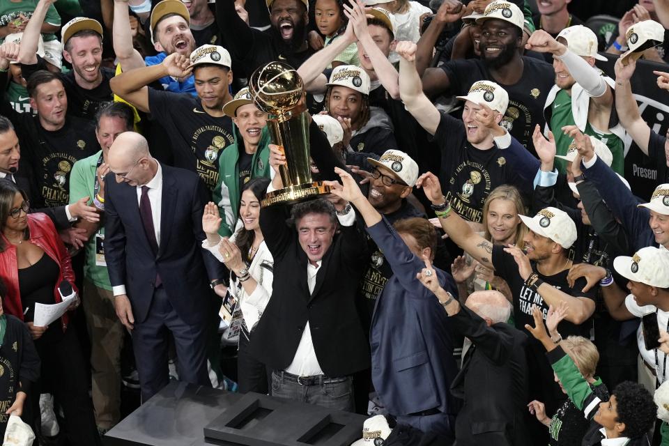 Boston Celtics owner Wyc Grousbeck raises the trophy after defeating the Dallas Mavericks in Game 5 of the NBA basketball finals, Monday, June 17, 2024, in Boston. (AP Photo/Michael Dwyer)