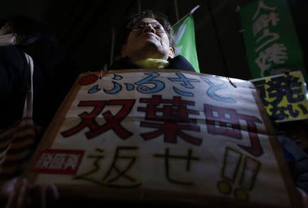 An evacuee from Futaba town in Fukushima prefecture holds a banner during an anti-nuclear rally in front of the headquarters of Tokyo Electric Power Co (TEPCO), the operator of the tsunami-crippled Fukushima Daiichi nuclear plant, a day before the five-year anniversary of the disaster, in Tokyo, Japan, March 10, 2016. The banner reads in Japanese "Please return my home, Futaba town". REUTERS/Yuya Shino