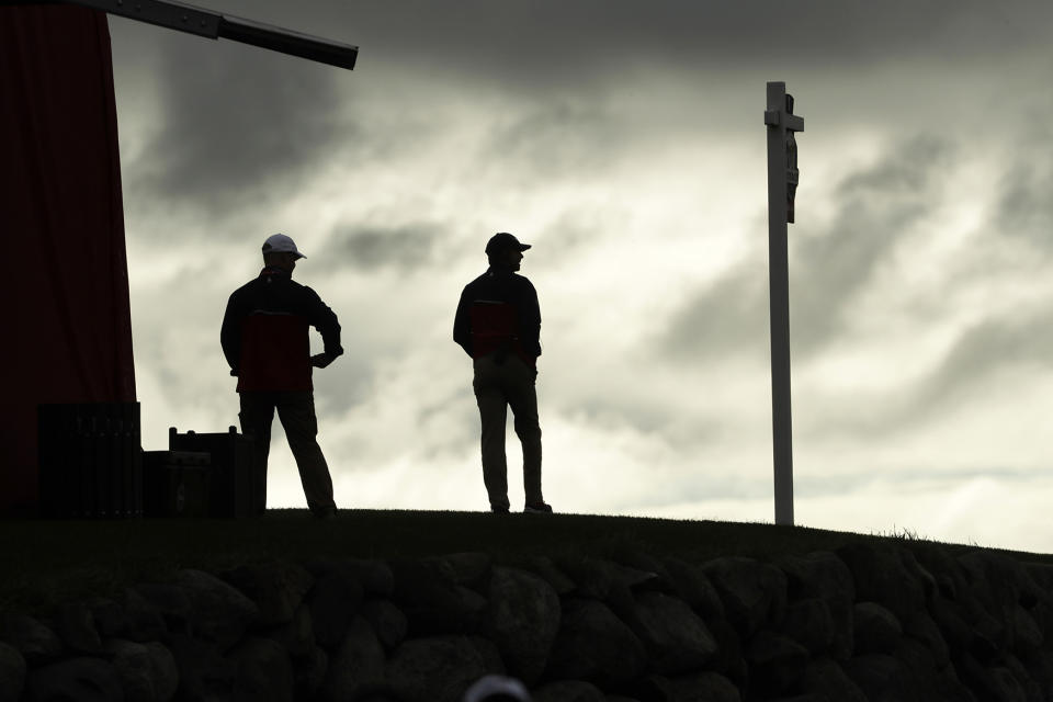 Marshals wait for players to arrive at the first tee for a practice round