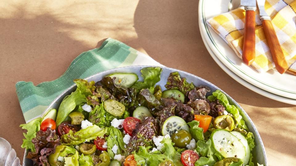 simple locally grown green salad in a bowl with silverware on a wooden table outside