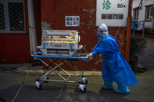 A medical worker wearing protective clothing against the new coronavirus pushes an incubator between buildings at a hospital in Beijing on February 21