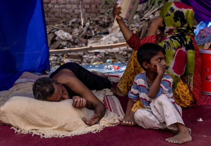 FILE PHOTO: A Rohingya refugee family rests in a temporary shelter after a fire destroyed a Rohingya refugee camp on Saturday night, in New Delhi