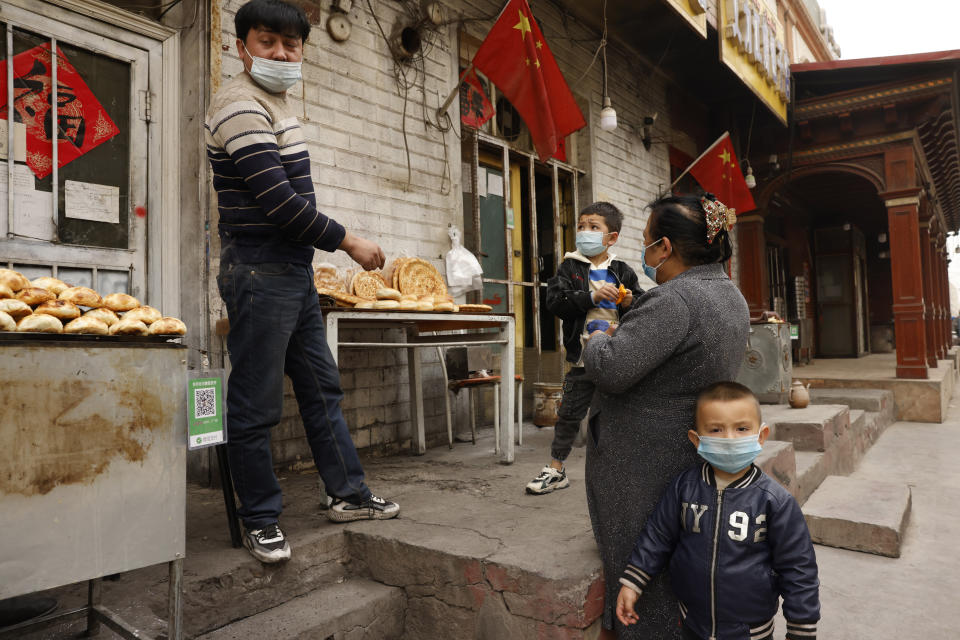 Locals buy bread from a street vendor in Shule county in western China's Xinjiang Uyghur Autonomous Region on Saturday, March 20, 2021. Xinjiang in far western China had the sharpest known decline in birthrates between 2017 and 2019 of any territory in recent history, according to a new analysis by an Australian think tank. (AP Photo/Ng Han Guan)