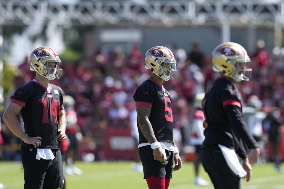 From left to right, San Francisco 49ers quarterbacks Sam Darnold and Trey Lance watch a pass thrown by Brandon Allen during NFL football training camp Sunday, July 30, 2023, in Santa Clara, Calif. (AP Photo/Godofredo A. Vásquez)