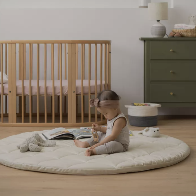 A photo of a baby playing on a Ted & Luna Round Playmat.