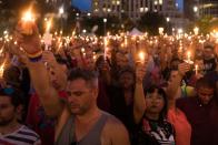 <p>People hold candles during an evening memorial service for the victims of the Pulse Nightclub shootings, at the Dr. Phillips Center for the Performing Arts in Orlando, Florida.</p>