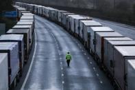 A man walks past lorries parked on the M20 motorway near Ashford