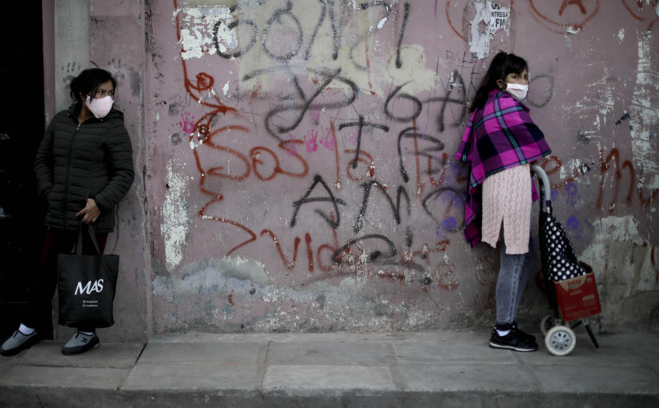 Women stand at a distance as they wait in line for a plate of food at a soup kitchen in the 1.11.14 neighborhood during a government-ordered lockdown to curb the spread of the coronavirus in Buenos Aires, Argentina, Friday, May 29, 2020. (AP Photo/Natacha Pisarenko)