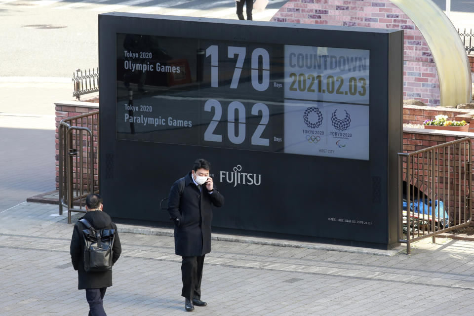 A man stands in front of a countdown clock for Tokyo Olympic and Paralympic Games in Tokyo, Wednesday, Feb. 3, 2021. Pressure is building on Japanese organizers and the IOC to explain exactly how they plan to hold the Tokyo Olympics in the midst of a pandemic. (AP Photo/Koji Sasahara)