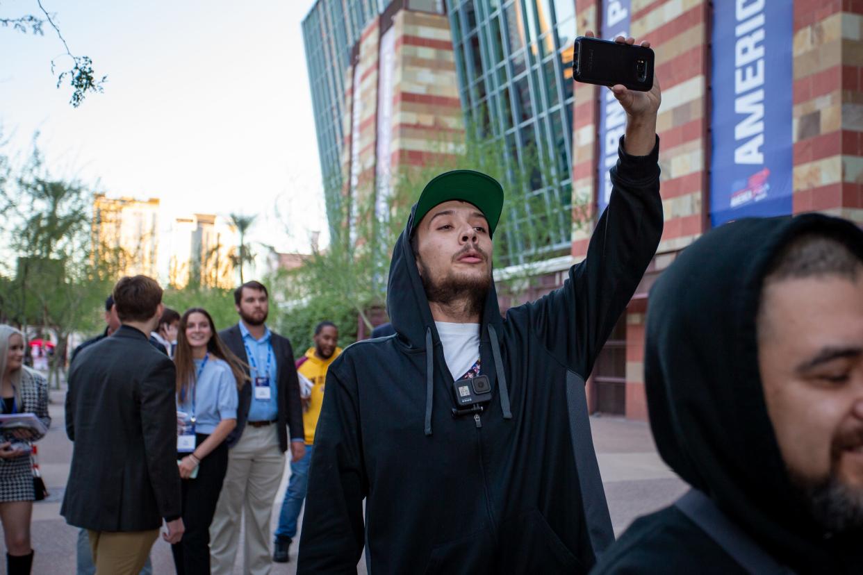 Darien Barrett, creator of the YouTube channel Tempe Against Police Violence, films Merissa Hamilton as she walks away outside the Phoenix Convention Center at the end of day 2 of Turning Point USA's AmericaFest on Dec. 19, 2021.