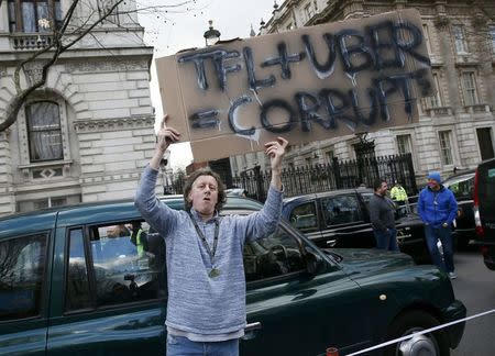 A London cab driver holds up a sign outside Downing Street during a protest against Uber on Whitehall in central London, February 10, 2015 REUTERS/Stefan Wermuth