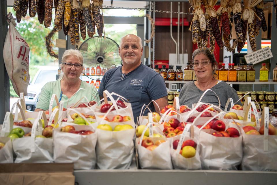 From left, Lynn Sealy, Myron Coates and Gina Campbell at the Coates Produce stand at the WNC Farmers Market, October 4, 2023.
