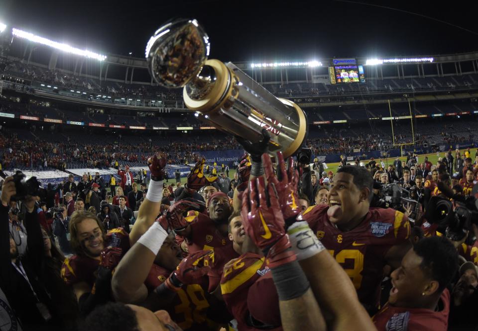 Dec 27, 2014; San Diego, CA, USA; Southern California Trojans players hoist the championship trophy after the 2014 Poinsettia Bowl against the Nebraska Cornhuskers at Qualcomm Stadium. USC defeated Nebraska 45-42. Mandatory Credit: Kirby Lee-USA TODAY Sports
