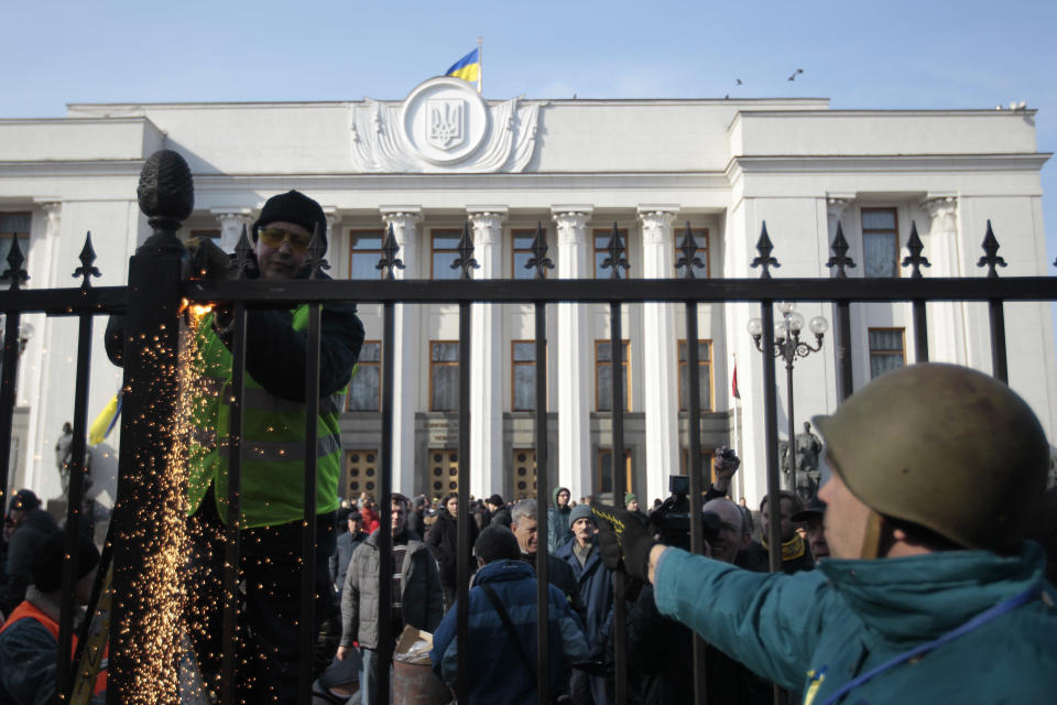 Anti-Yanukovych protesters remove a fence that surrounds Ukraine's parliament in Kiev, Wednesday, Feb. 26, 2014. Ukraine has been consumed by a three-month-long political crisis. President Viktor Yanukovych and protest leaders signed an agreement last week to end the conflict that left more than 80 people dead in just a few days in Kiev. Shortly after, Yanukovych fled the capital for his powerbase in eastern Ukraine but his exact whereabouts are unknown. (AP Photo/Sergei Chuzavkov)