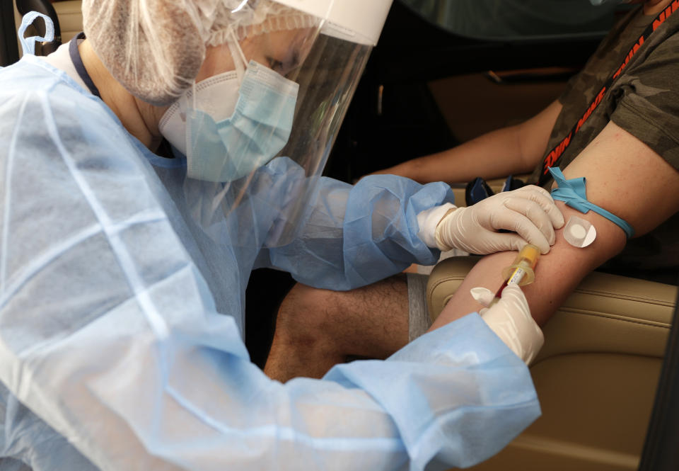 A health worker takes blood to perform an Enhanced Chemiluminescence Immunoassay (ECLIA) antibody test at a drive-thru COVID-19 testing facility at a hospital in metropolitan Manila, Philippines on Wednesday, July 8, 2020. Philippine President Rodrigo Duterte eased one of the world's longest lockdowns in the Philippine capital of more than 13 million people on June 1 after the economy shrank in the first quarter in its first contraction in more than two decades. (AP Photo/Aaron Favila)