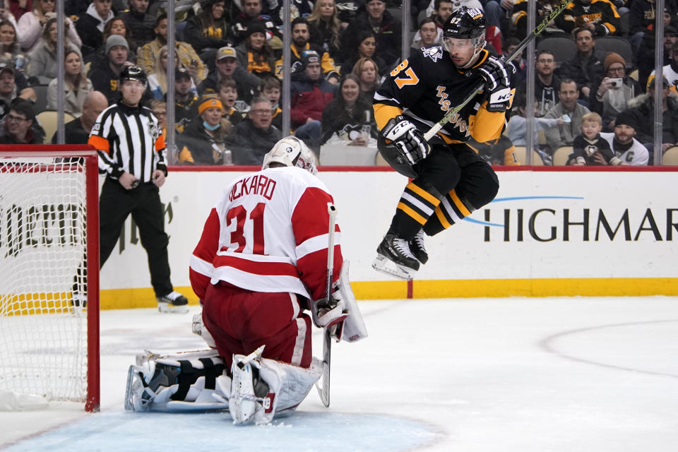 Pittsburgh Penguins' Sidney Crosby (87) leaps to avoid a shot on Detroit Red Wings goaltender Calvin Pickard (31) during the second period of an NHL hockey game in Pittsburgh, Friday, Jan. 28, 2022. (AP Photo/Gene J. Puskar)