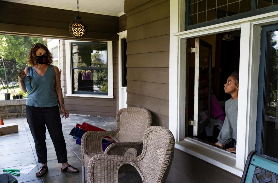 Former third-grade teacher Kristen Bristow listens to her daughter Andie, 6, on the porch of their Craftsman-style home.