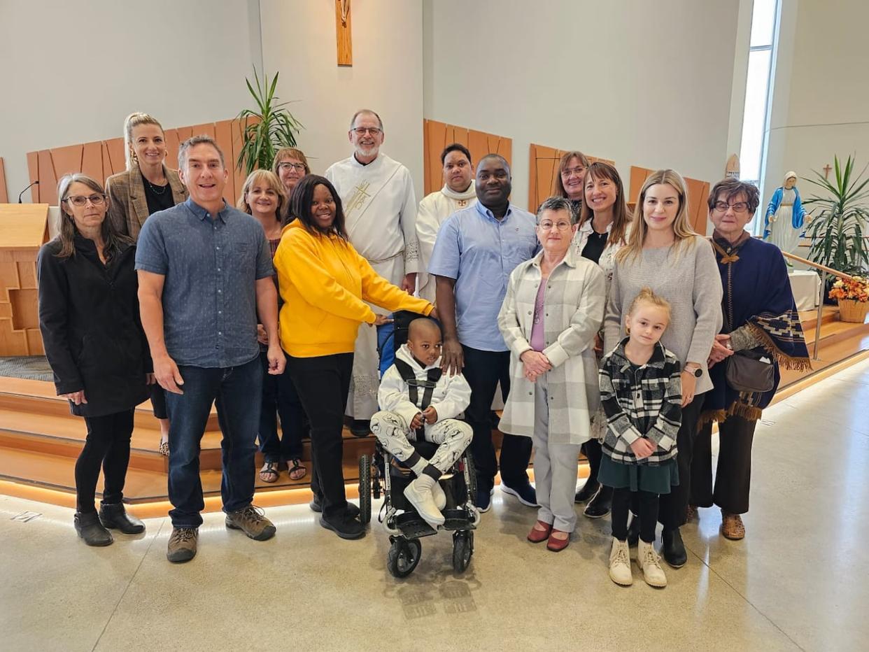 Beatrice Agbonavbare, her husband Senator and their five-year-old son Michael, centre, with their Christ The Redeemer Roman Catholic Church family in Swift Current. Suzie Berg, fourth from right in the back row, student services co-ordinator for Holy Trinity Catholic Schools, helped the Agbonavbares get Michael into school as soon as she could. (Submitted by Beatrice Agbonavbare - image credit)