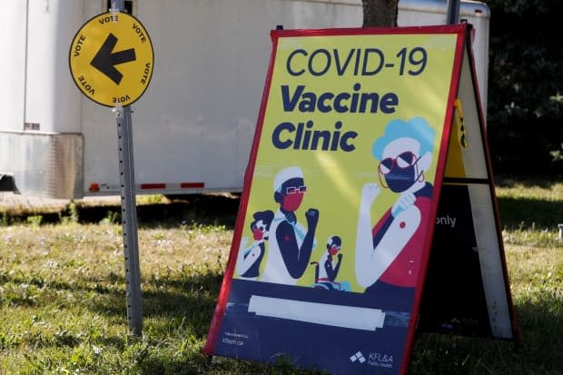 Signs for a voting station and COVID-19 vaccine clinic sit side-by-side in Kingston on Monday, election day. (Lars Hagberg/Reuters - image credit)