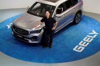 Zhejiang Geely Holding Group's Chairman Li Shufu poses for pictures next to a Xingyue L SUV at Geely headquarters in Hangzhou
