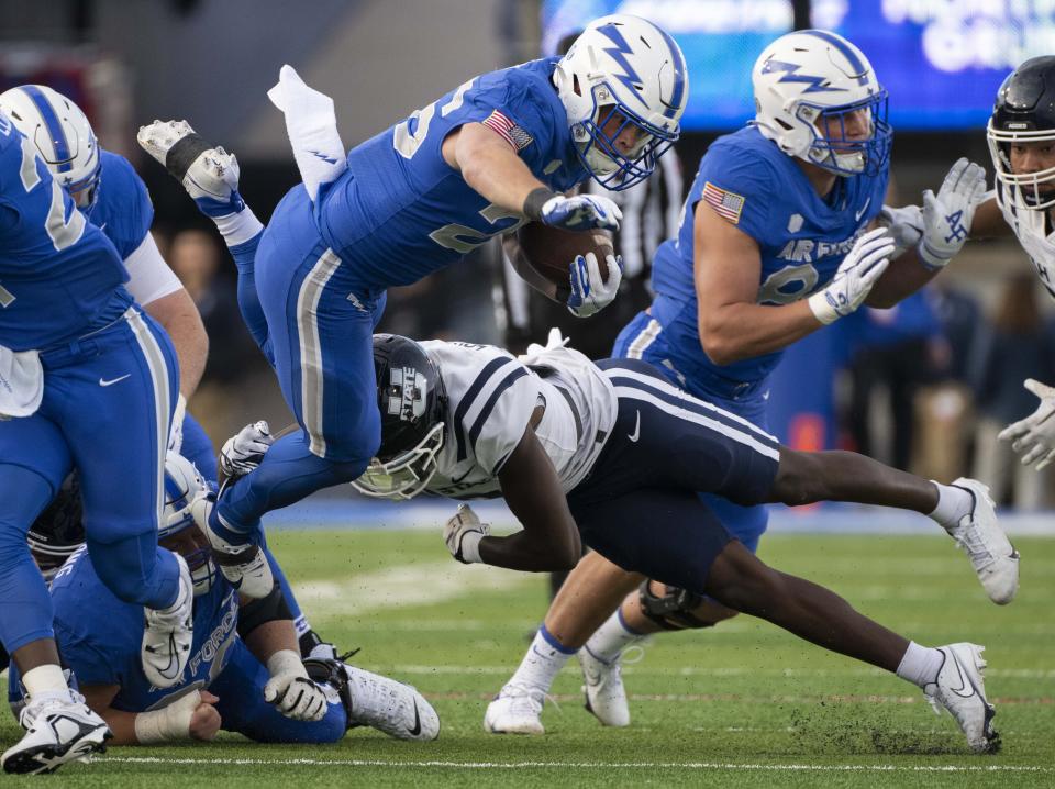 Air Force running back Owen Burk, center top, leaps over a tackle-attempt by Utah State safety Ike Larsen, center bottom, for a first down during the first half of an NCAA college football game in Air Force Academy, Colo., Friday, Sept. 15, 2023. | Christian Murdock/The Gazette via AP