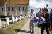 British expatriate Steven Oldrid, left, checks a list as he directs people where to lay wooden crosses with names of WWII dead and flowers during D-Day ceremonies at the local war cemetery in Benouville, Normandy, France on Saturday, June 6, 2020. Due to coronavirus measures many relatives and veterans will not make this years 76th anniversary of D-Day. Oldrid will be bringing it to them virtually as he places wreaths and crosses for families and posts the moments on his facebook page. (AP Photo/Virginia Mayo)