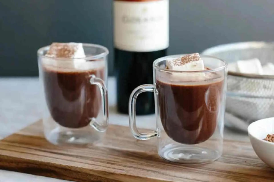 Tazas de chocolate caliente con una botella de vino tinto