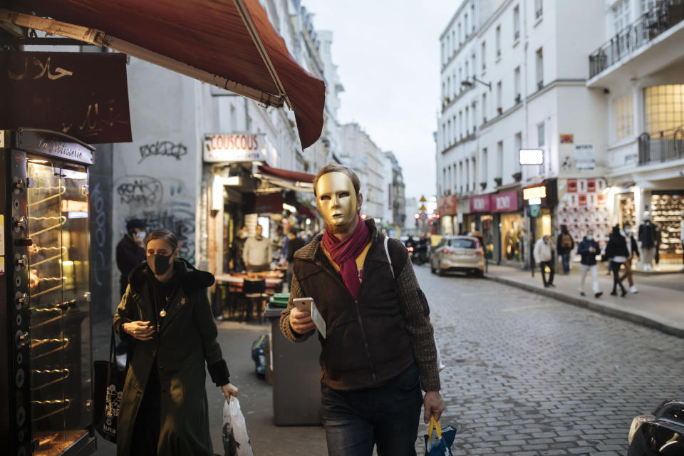 A man wear a golden mask costume walks down a street in Paris, Thursday Oct.29, 2020. Some doctors expressed relief but business owners despaired as France prepared to shut down again for a month to try to put the brakes on the fast-moving virus. The new measures are set to come into effect at midnight. (AP Photo/Lewis Joly)