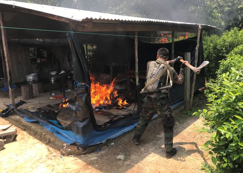 Peruvian anti-narcotics police officer uses an ax after burning down a cocaine paste laboratory in Caballococha