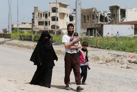 Members of an Iraqi displaced family walk as they flee after a battle between the Iraqi rapid response forces and Islamic State militants in western Mosul, Iraq, April 22, 2017. REUTERS/Muhammad Hamed