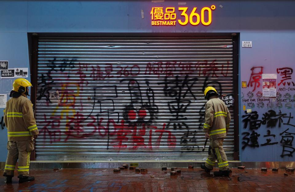Firemen check a shop vandalized by protesters in Hong Kong, Wednesday, Jan. 1, 2020. Hong Kong toned down its New Year’s celebrations amid the protests that began in June and which have dealt severe blows to the city’s retail, tourism and nightlife sectors. (AP Photo/Vincent Yu)