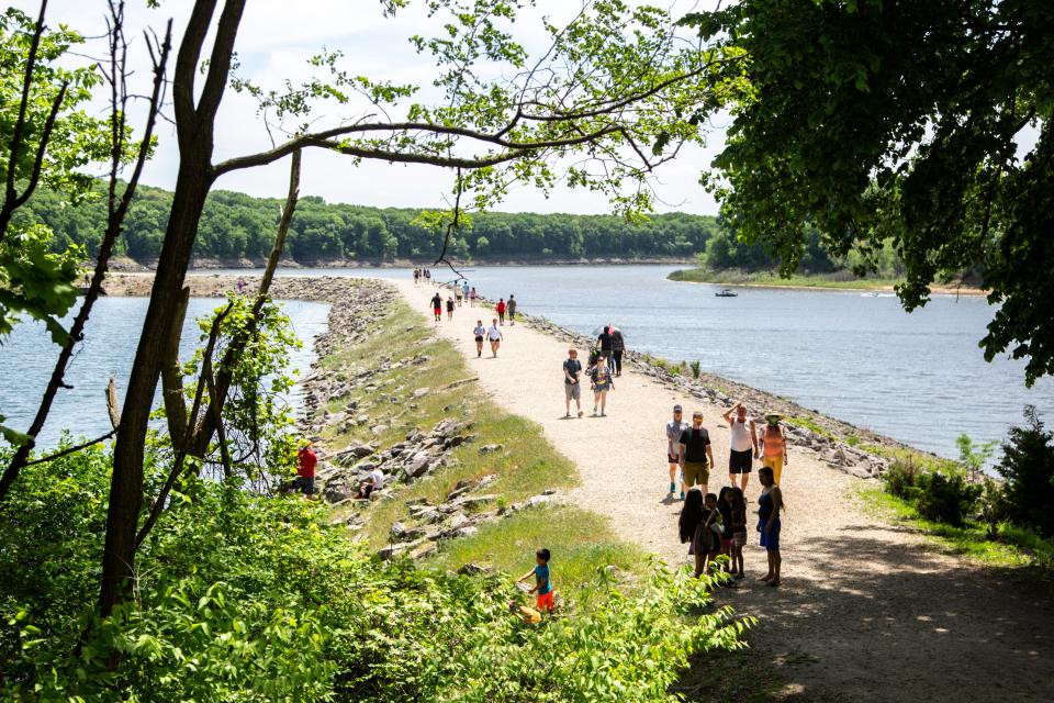 People walk along a dam between the Iowa River and Lake Macbride on Memorial Day during the novel coronavirus pandemic, Monday, May 25, 2020, at Lake Macbride State Park in Johnson County, Iowa.