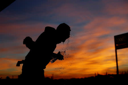 A migrant from Honduras, part of a caravan of thousands traveling from Central America en route to the United States, washes his face with water from a plastic bottle at a makeshift camp at a gas station where the migrants wait for buses in Navojoa, Mexico November 16, 2018. REUTERS/Kim Kyung-Hoon