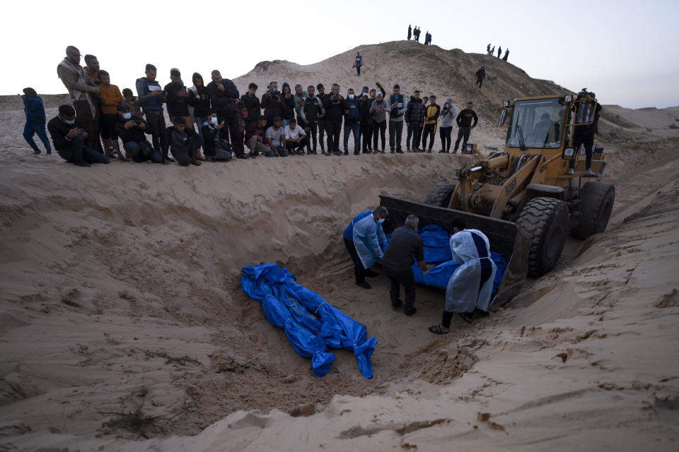 A bulldozer unloads the bodies of Palestinians killed in fighting with Israel and turned over by the Israeli military during a mass funeral in Rafah, Gaza Strip, Tuesday, Dec. 26, 2023.(AP Photo/Fatima Shbair)