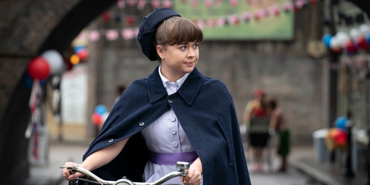 call the midwife nancy corrigan in her uniform walking with her bicycle