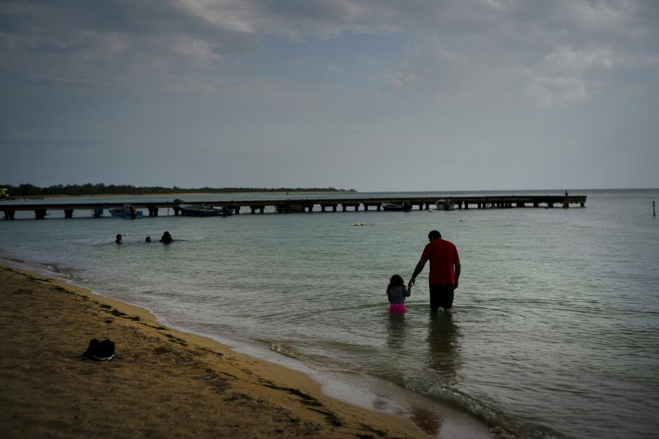 Eduardo Torres, from Puerto Rico, walks with his daughter in the ocean before the arrival of Tropical Storm Dorian in Combate, Puerto Rico, Aug. 27, 2019. (Photo: Ramon Espinosa/AP)