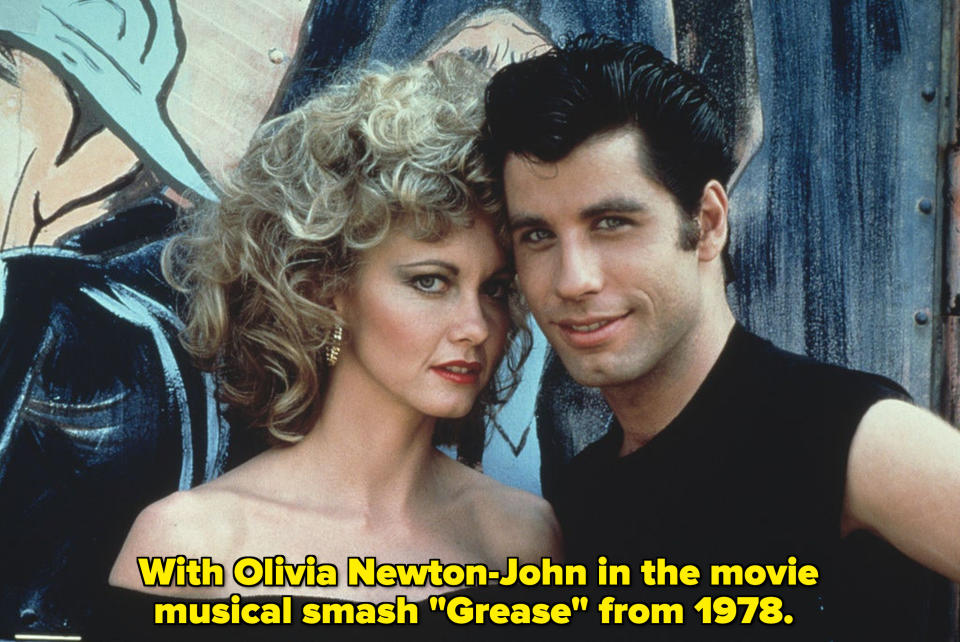 Olivia Newton-John and Travolta stand together and smile in "Grease"